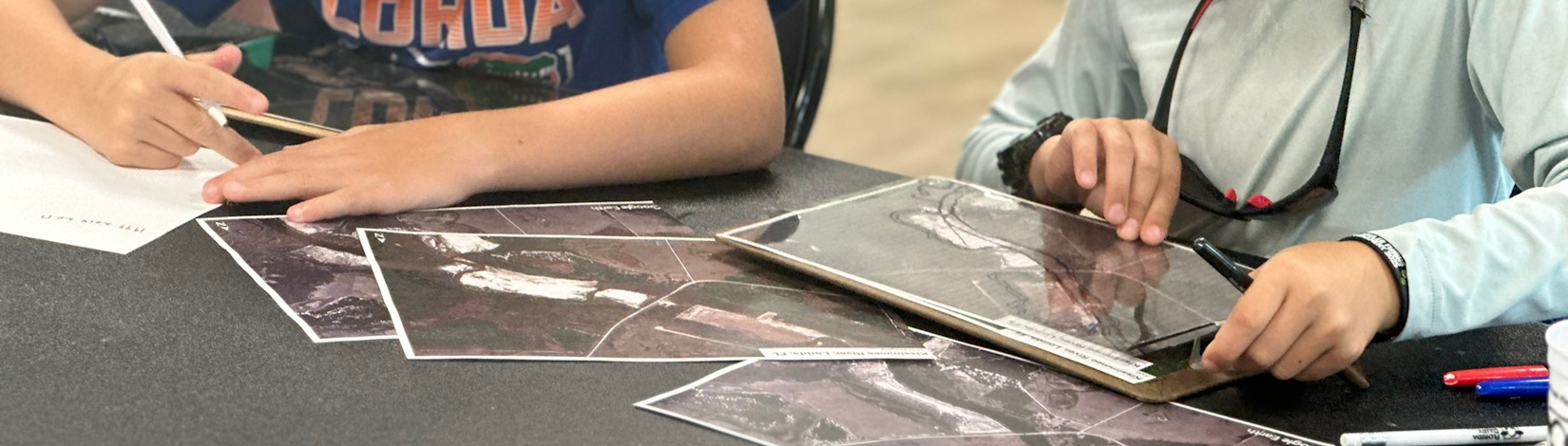 Close up of youth creating maps of a river from a series of aerial photographs.