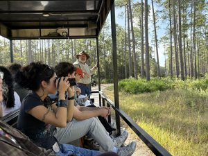 SFFGS Assistant Director Scott Sager speaks to Video Art students as they ride on a tram through the Austin Cary Forest.
