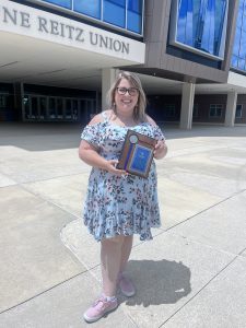 Danielle Shu stands holding the UF 2023 Career Influencer Award in front of the J. Wayne Reitz Union