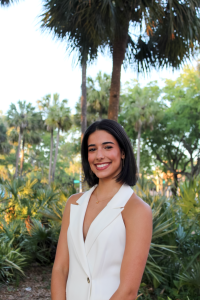 Alumni of Food and Resource Economics Combined Degree program Victoria Manrique posts outdoors wearing business professional attire.