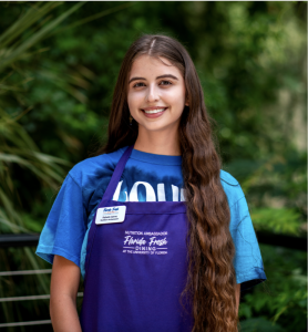 Rafaella standing outside wearing a blue shirt and apron, autism | Food Science and Human Nutrition UF/IFAS