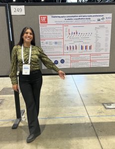 Sofia wearing a green shirt and black pants presenting a poster at a nutrition conference, curcumin | Food Science and Human Nutrition UF/IFAS