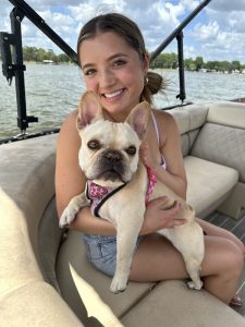 Presley holding a small white dog while sitting in a boat.