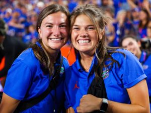 Julia and a colleague wearing blue Gator polos and smiling in front of a large crowd, sports nutrition | Food Science and Human Nutrition UF/IFAS, UAA Communications photo by Maddie Washburn