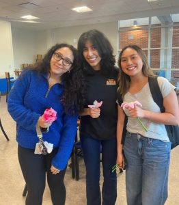 Three women holding pipe cleaner flowers.