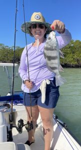 Melissa standing on a boat holding a fishing pole and fish.