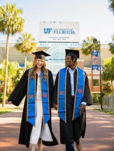 Julia and her fiancé wearing graduation robes with trees and a large UF building in the background, encourage | Food Science and Human Nutrition UF/IFAS