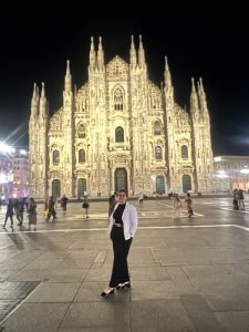 Melissa standing in front of the Duomo di Milano (Milan Cathedral) in Milan, Italy at night.