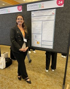Melissa wearing a dark suit and standing in front of a poster, facial pain | Food Science and Human Nutrition UF/IFAS
