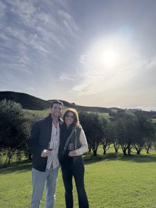 Zachary and his mother standing in front of trees and blue sky.