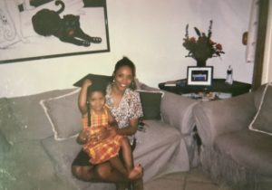 An older photo of baby Rachel wearing a graduation cap and sitting on her cousin's lap.