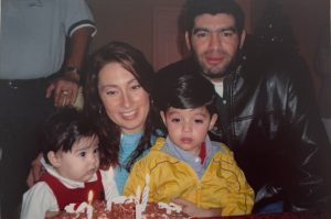Picture of a couple with two kids behind a birthday cake.