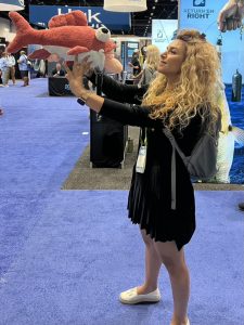 Dr. Farzad in the middle of a conference holding a large orange fish stuffie.