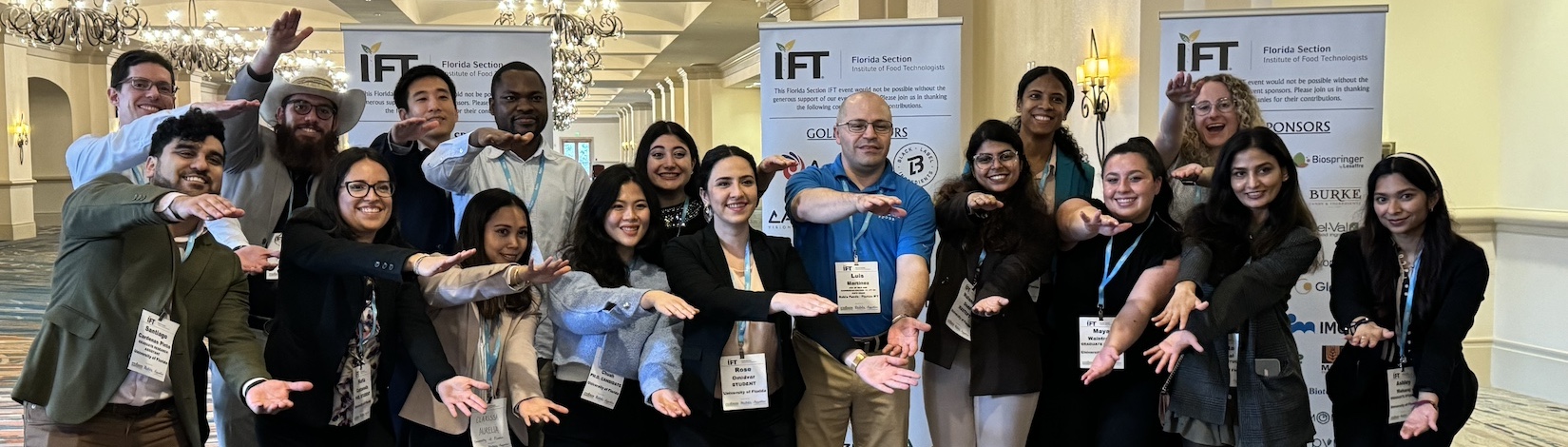 A large group of student doing the Gator Chomp inside a large, carpeted room.