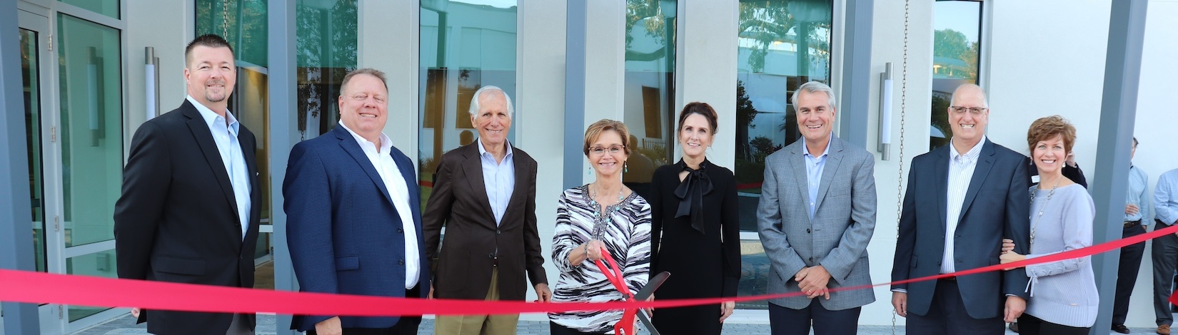 Nina stands with colleagues in front of new Innovation Center cutting a red ribbon with scissors | Food Science and Human Nutrition UF/IFAS