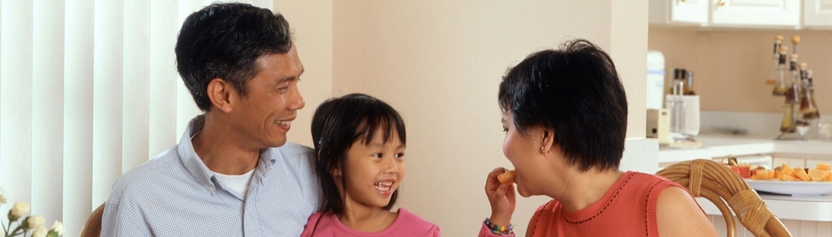 Girl playfully interacting with parents during meal time.