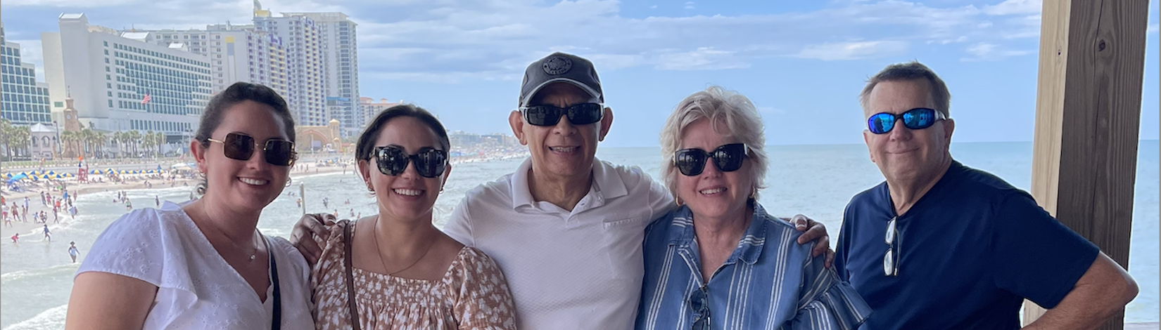 Melissa with her family in front of a beach.