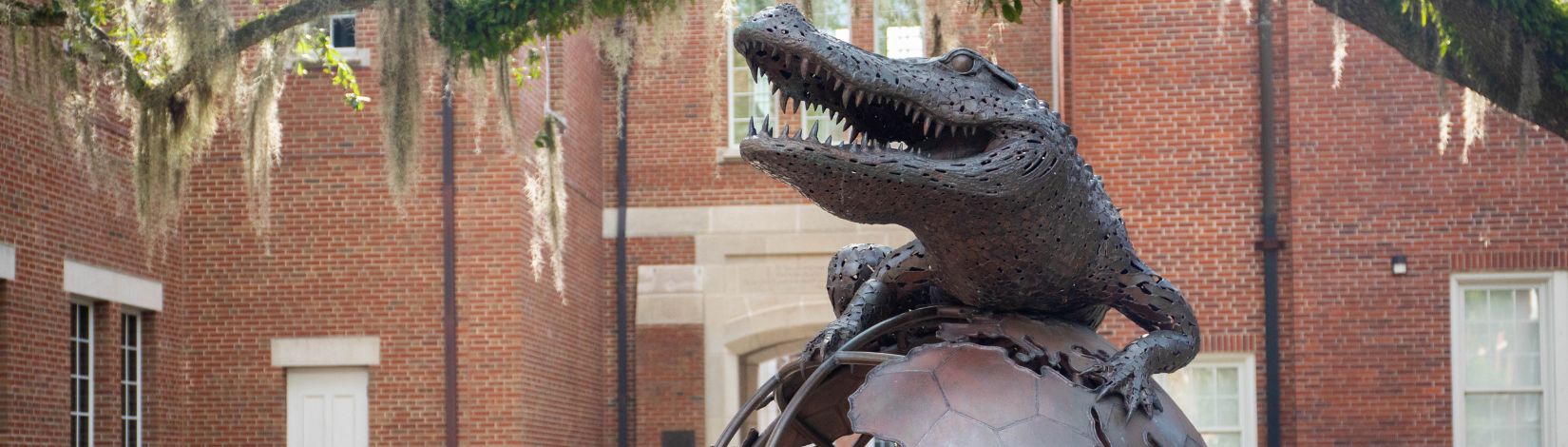 The Gator Ubiquity statue, a bronze sculpture of a gator climbing a globe outside of Heavener Hall.