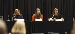 Elena Bottemiller, Dr. Court, and Dr. Grunwald sitting at their panelist table at the Future of Food Forum with a black background