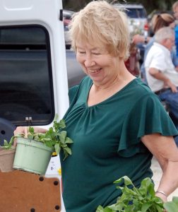 woman carrying two containers of green plants