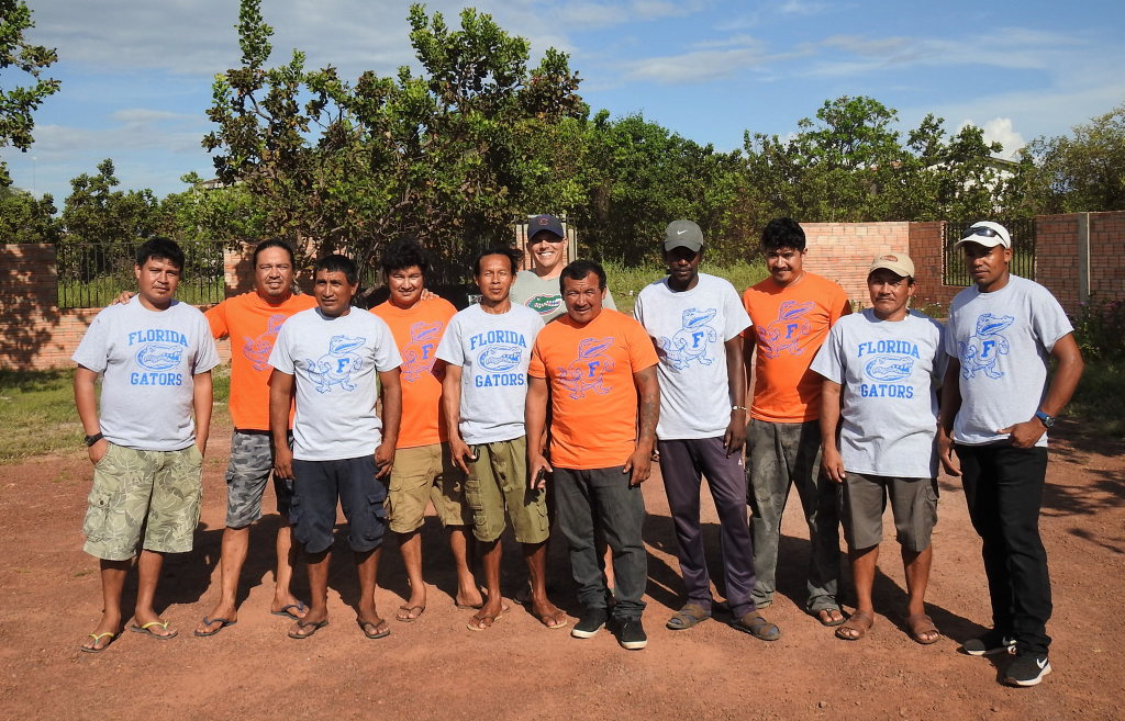 A group of Rupununi men and Dr. Hallett. They are wearing UF t-shirts and posing outside. 