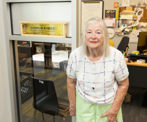 Vera Damron next to an office at the UF/IFAS HBREL displaying a placard which reads "In Memory of DAMRON FAMILY William Henry & Effie Eugenia, Dr. Bobby Leon"