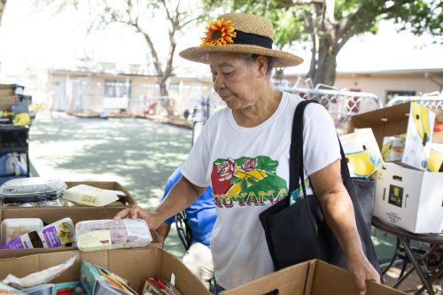A woman browsing a selection of meats at a food pantry. Photo taken 06-26-18.