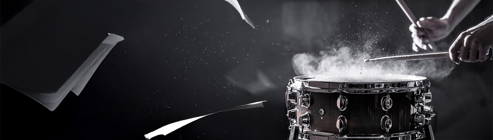 pages and dust fly while a drummers hands are shown performing a drum roll on a snare drum