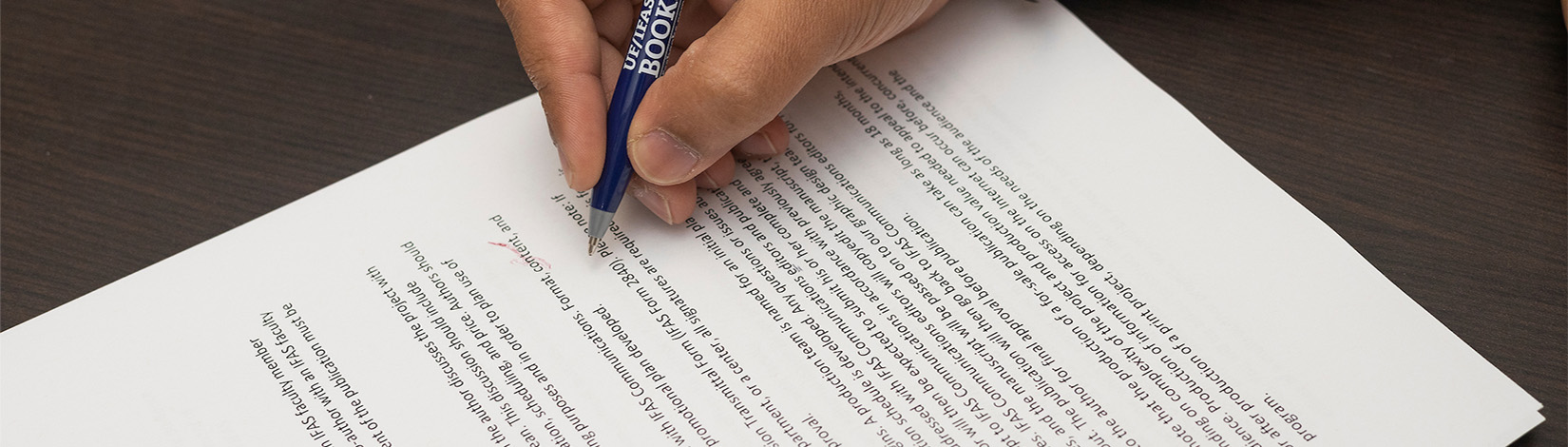 close up of hand holding a pen editing a printed document.
