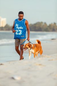A man walks a dog on the beach. 