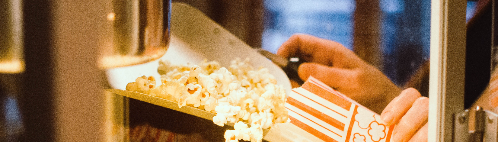 A person empties the popcorn maker at a movie theater.
