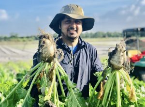 Graduate student presents beets produced in an experimental field 