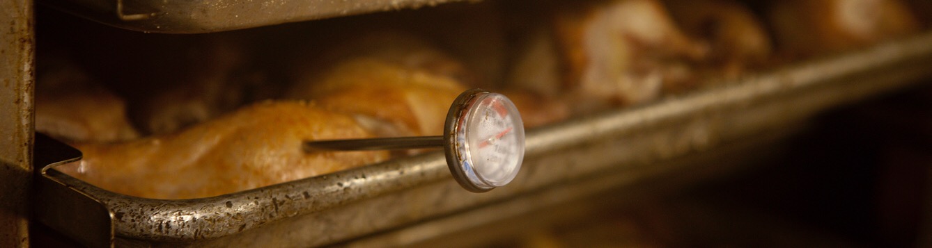 A food thermometer checking the cooking temperature of chicken.