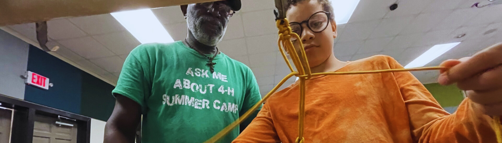 Adult helping youth weave a bracelet