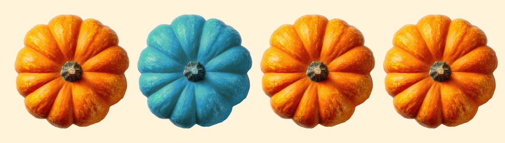 Four pumpkins in a row. Three are orange and one is teal.