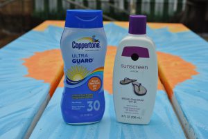 Two bottles of sunscreen on a picnic table