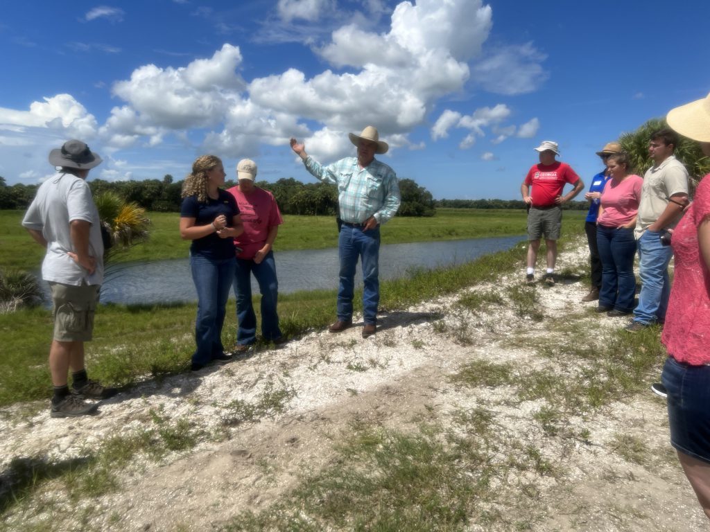 A rancher shares information with extension agents during a tour of his ranch and water farm