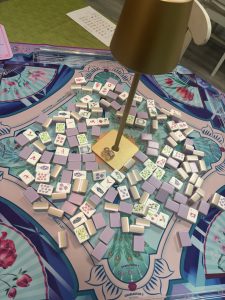 Players’ mahjong tiles laid out on a table during a game.