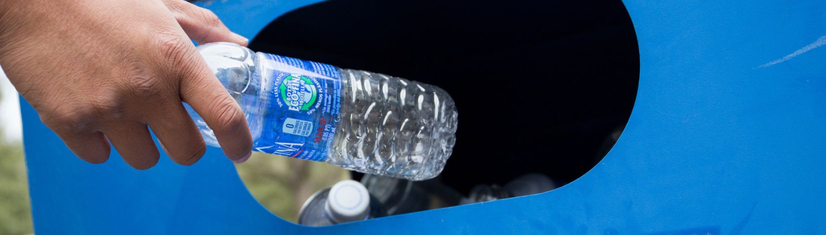 Plastic bottle being put into a recycle bin.