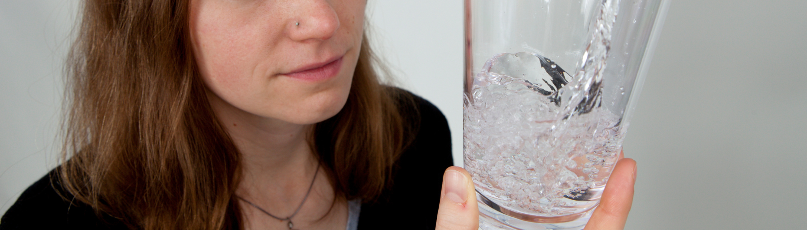 A woman holding onto and looking at a glass of water.