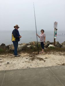 Two people fishing near a bird rescue sign.