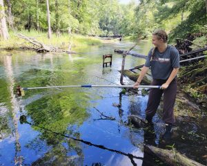 Amelia collecting a water sample at Gilchrest Blue Springs. Photo Credit: Ron Fox. 