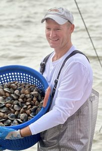 Man holding basket of clams.