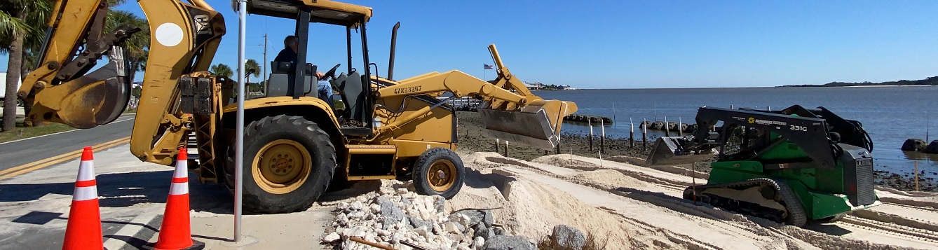 two machines work along a shoreline