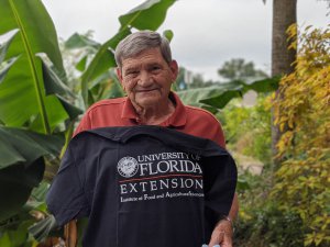 Mr. Starnes smiles with UF/IFAS Extension t-shirt in garden