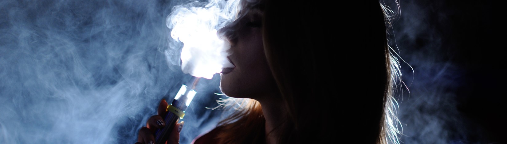 A woman exhaling smoke while vaping