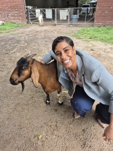 Pamela Aracena Santos with a brown goat outdoors