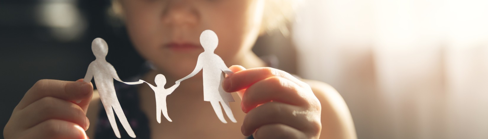 A little child holding a paper representation of a family