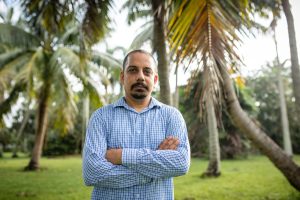 Professor Braham Dhillon standing in front of palm trees and a grassy area.