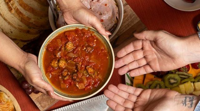 Hands passing a dish during holiday meal.